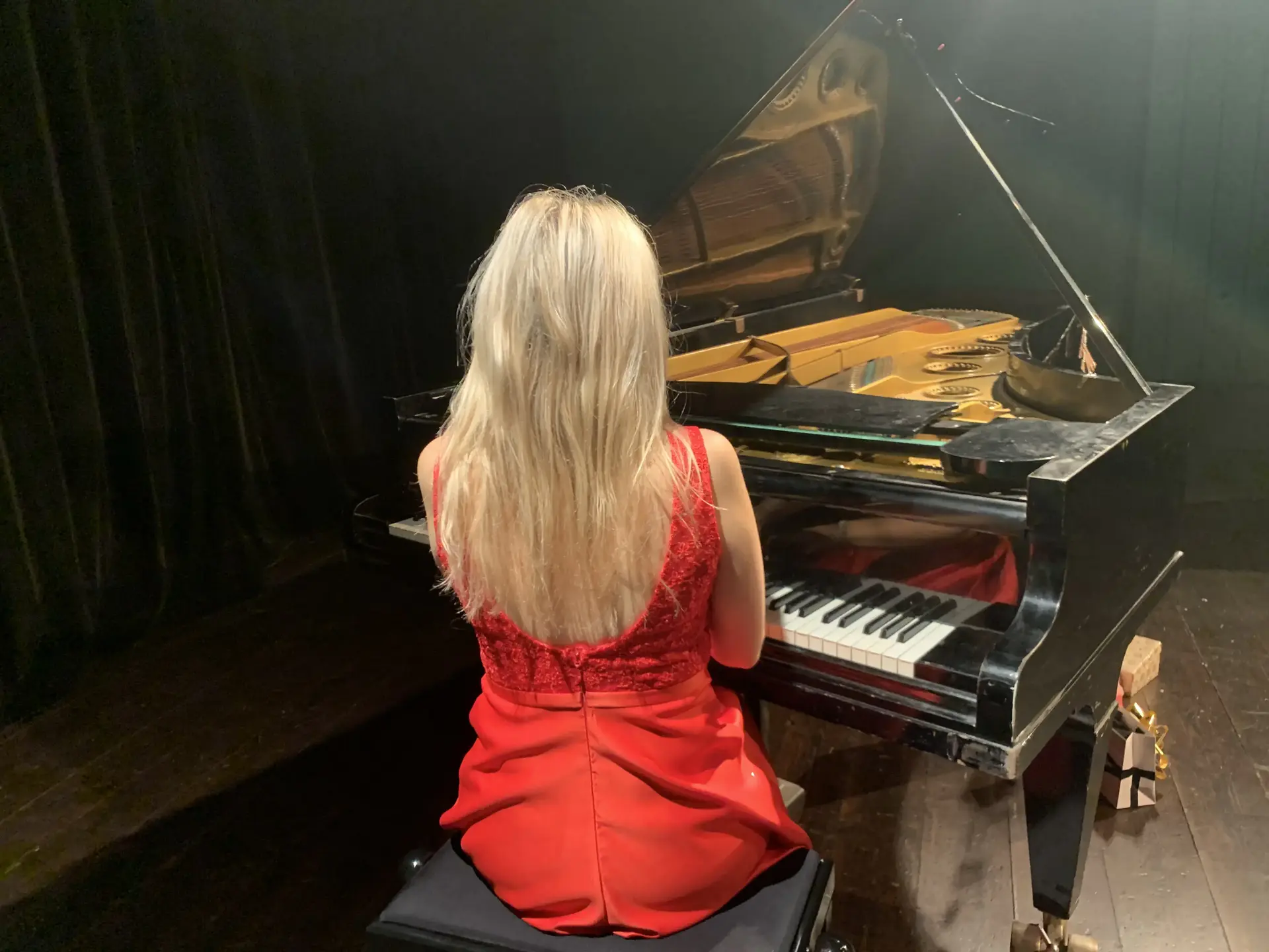 Maria Millini vid flygel i röd klänning