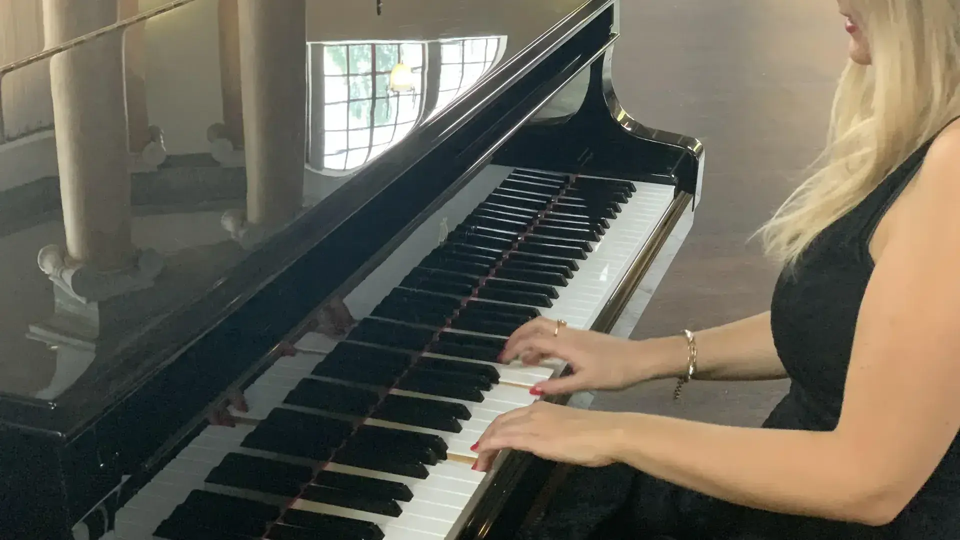 Maria Millini vid piano i elegant svart klänning